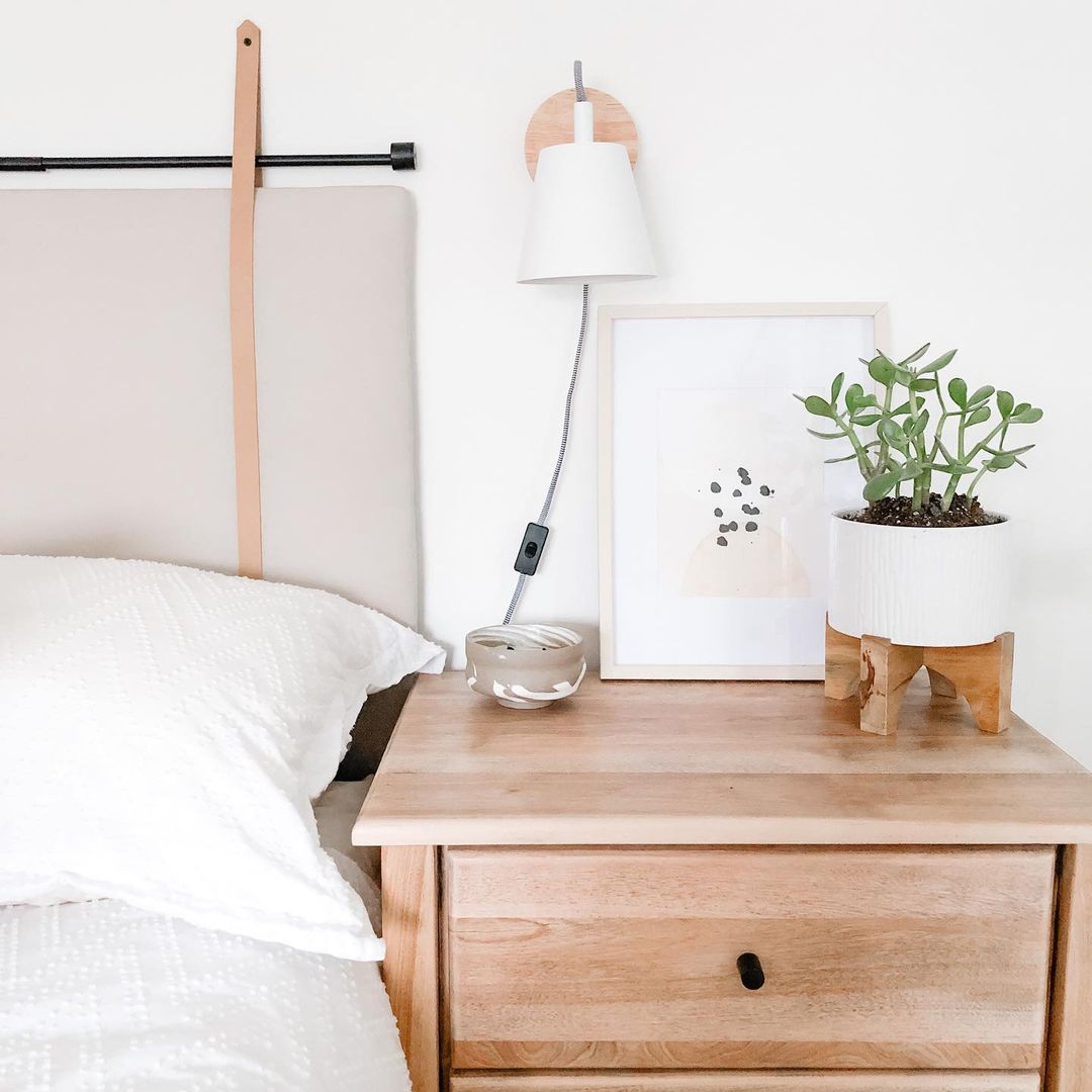 a bed with sidetable and jade plant in a small pot
